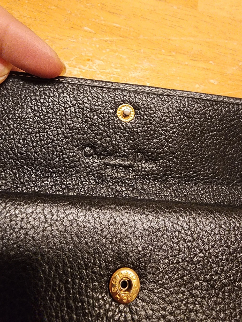 black Christian Dior pebbled leather trifold long wallet featuring gold-tone 